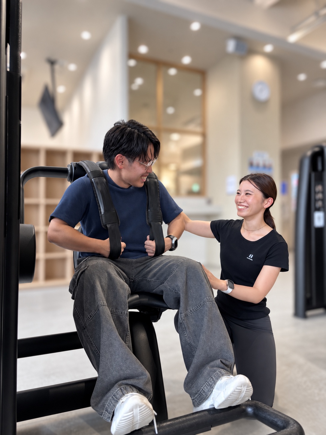 笑顔で運動する男性と、そばでサポートする女性スタッフ